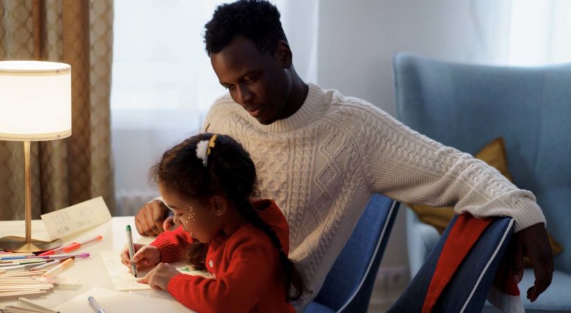 Man watches as young girl writes or draws with markers