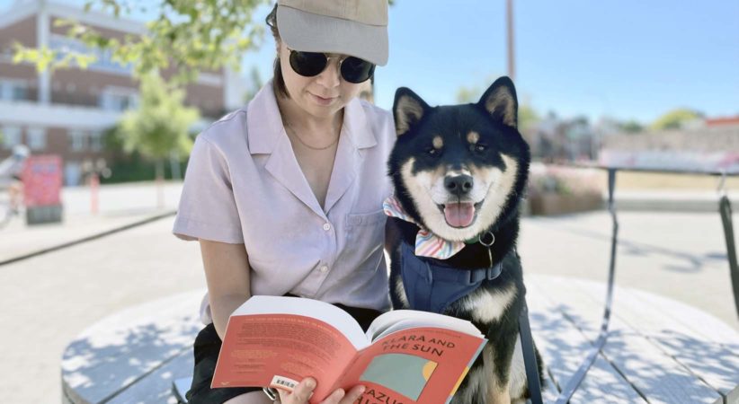Gunner the dog and his owner reading a book outside