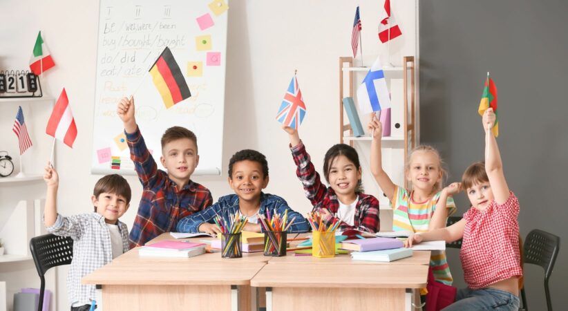 A group of children in a classroom holding up flags from different countries
