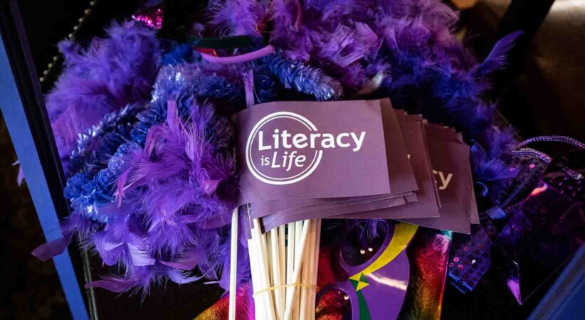 A "literacy is life" flag lying on top of purple costume accessories.