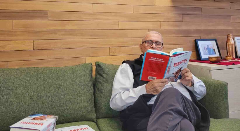 Chief Dr. Robert Joseph reading his book while sitting on a couch.