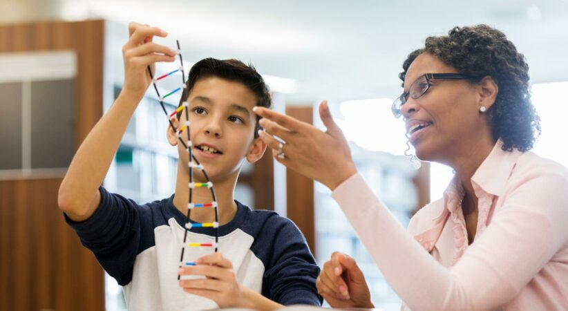 A child and an adult examine a model of DNA.