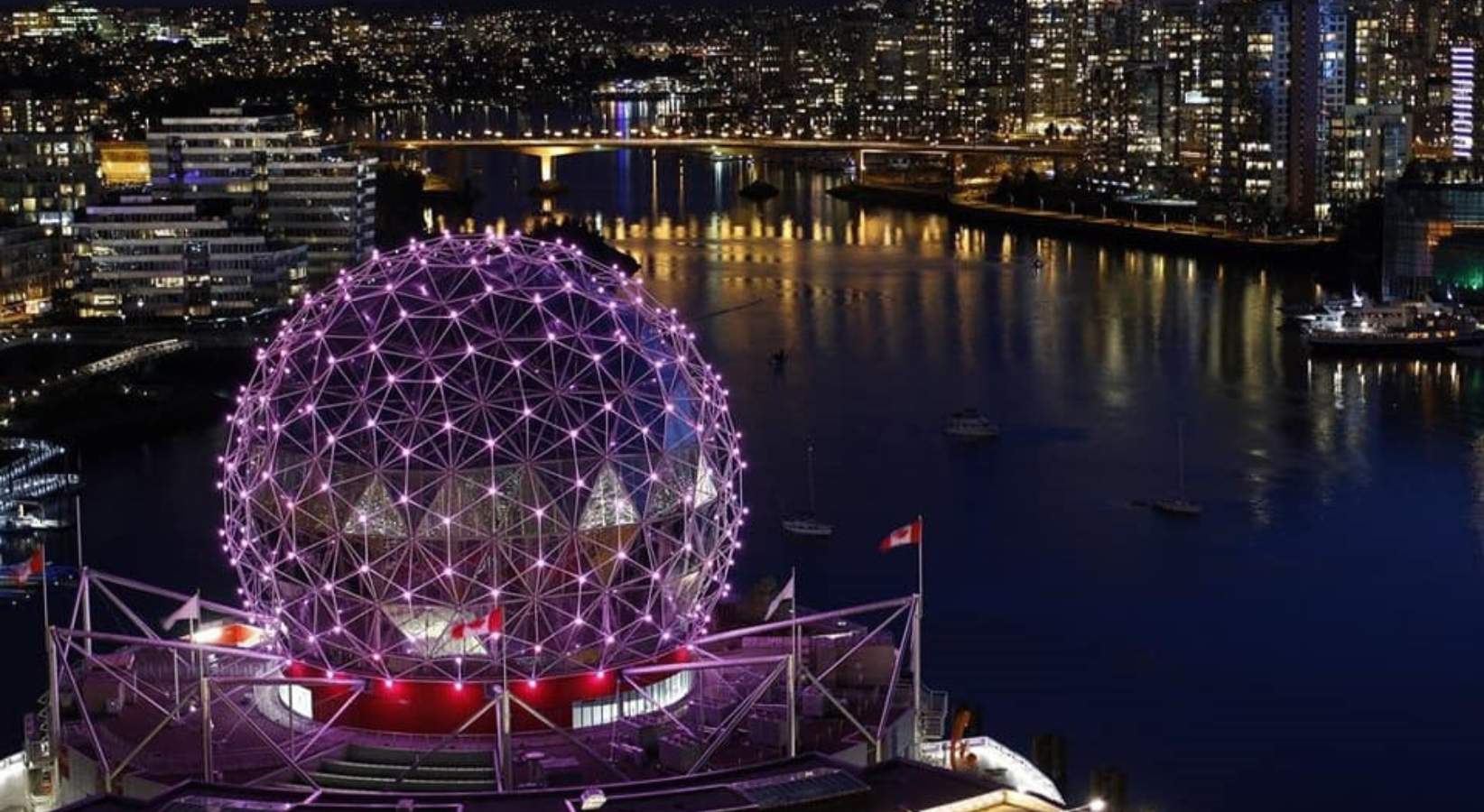 Science World Vancouver lit with purple lights and the city in the background.