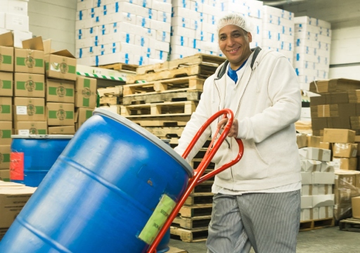 Man in a warehouse moving a blue canister