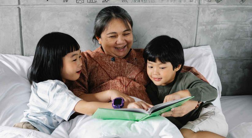 A woman reads to to children in bed.